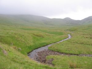 NN685338 looking SSE along the Finglen Burn. On the left (in the cloud) is the Corbett, Creag Uchdag, while the right of way from Loch Tay to Comrie goes alongside this burn and over the col to the right of the obvious knoll on the skyline (2008). © Andrew Spenceley, Geograph