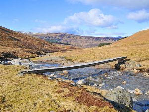 NN571437: footbridge over the Allt Bail' a' Mhuillinn. Note the cable attached to the centre of the bridge, presumably to stop it being washed away in a spate. © Dr Richard Murray, Geograph