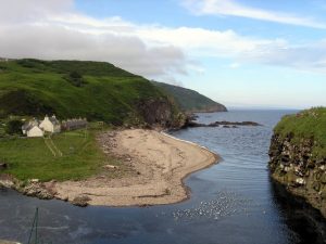 Looking north onto the entrance to Berriedale Harbour and the pebble beach in 2007. The remains of the castle are just visible on the right. The large white building is the old net store and beyond it are the remains of four fisher cottages. © Sarah Egan, Geograph