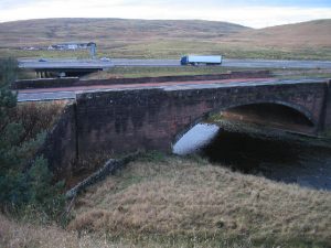 NS957182: near Elvanfoot the B7076 crosses the River Clyde. In the foreground of this photo (2003), barely discernible, is the graveyard of 37 Irish navvies who died during the construction of the Carlisle to Glasgow Railway. © Ian Mitchell, Geograph